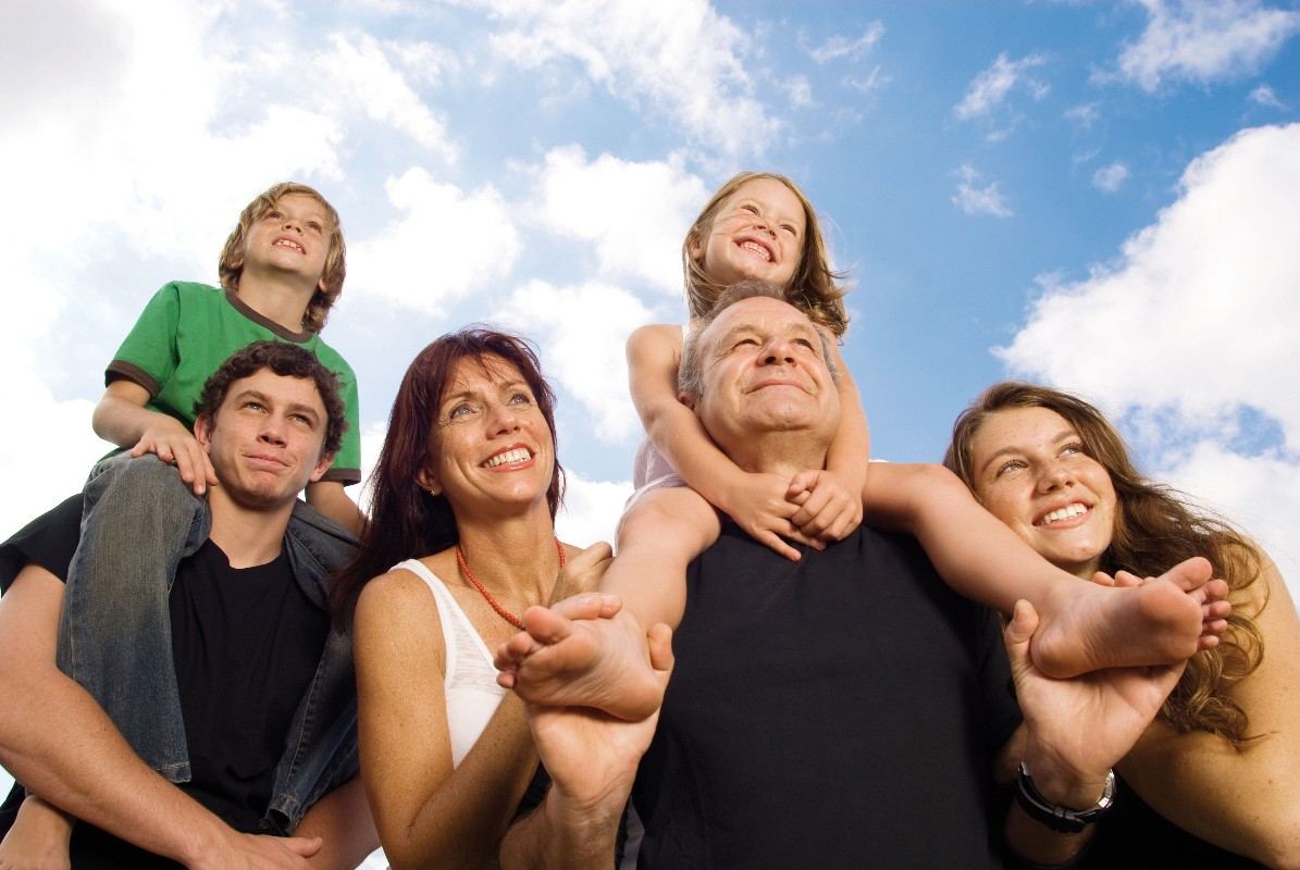 Familia sonriente mirando al cielo, protegida con un seguro de vida familiar de ARCA Asesores