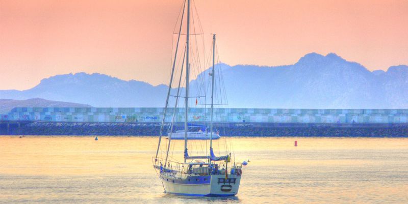 Velero navegando al atardecer, embarcación asegurada