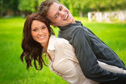 Pareja joven sonriendo en un parque, protegida con un seguro individual